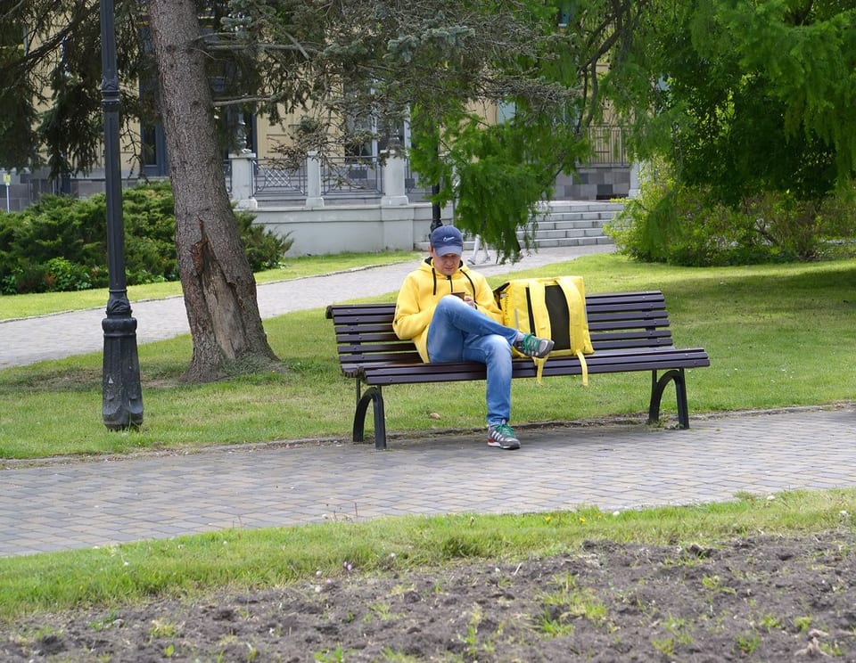 Курьер отдыхает на скамейке в парке