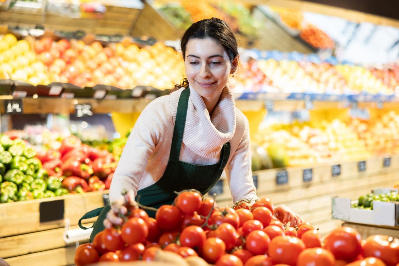Продавец раскладывает продукты на прилавке